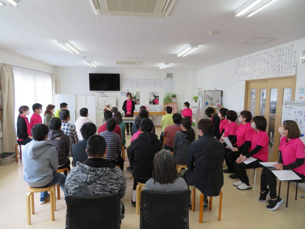 理事長の話を聞く利用者とスタッフ